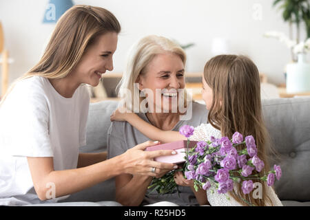 Happy grandma thanking grandchild and grown daughter for flowers Stock Photo