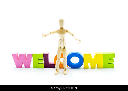 Wooden figure posing as business man in front of the word WELCOME, high key isolated on white. Stock Photo