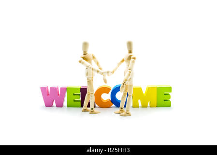 Wooden figures posing as business men shaking hands in front of the word WELCOME, high key isolated on white and copy space Stock Photo