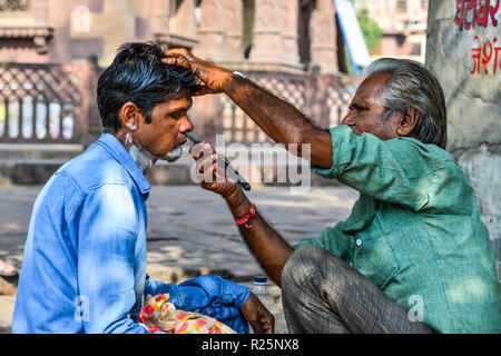 Jodhpur, India - Nov 6, 2017. A man gets a shave at a street barber shop in Jodhpur, India. Jodhpur is the second largest city in state of Rajasthan. Stock Photo