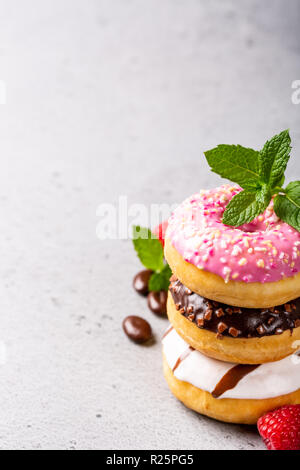 Stack of colorful donuts on gray concrete background. Party food concept with copy space. Stock Photo