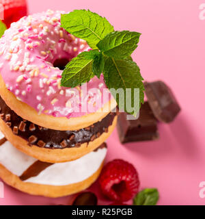 Stack of colorful donuts on pink background. Party food concept. Stock Photo