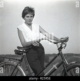 1960s, attractive young woman with her bicycle on a path in the countryside. Stock Photo