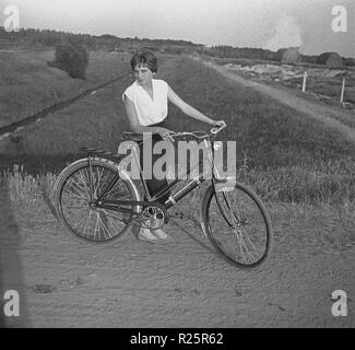 1960s, attractive young woman with her bicycle on a path in the countryside. Stock Photo