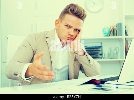 Frustrated young man having business problems with papers at workplace Stock Photo