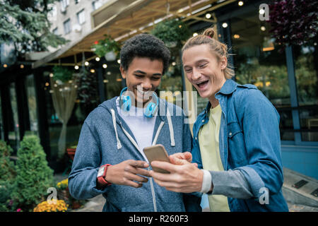 Delighted male friends discussing a new smartphone Stock Photo