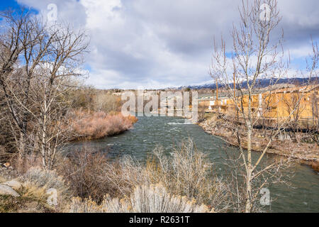 Truckee River flowing through a residential neighborhood in Reno, Nevada; snow covered mountains in the background Stock Photo