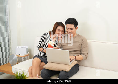 Young couple surfing on internet with laptop. Modern white apartment in background Stock Photo