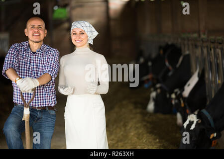 Two smiling farmers taking a pause in hangar with cows Stock Photo - Alamy