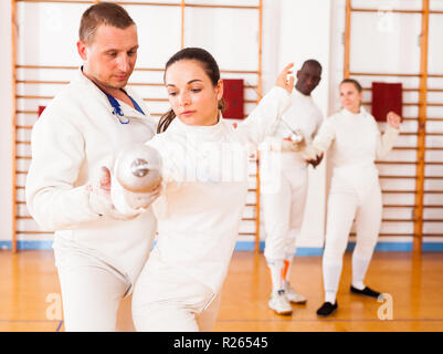 Female fencer practicing  movements with trainer at fencing workout Stock Photo