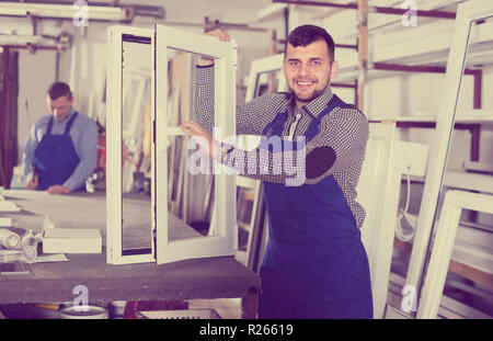 Workman is demonstrating the window frame in workshop. Stock Photo