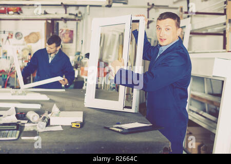 Two smiling cheerful positive careful workmen inspecting PVC manufacturing output in workshop Stock Photo