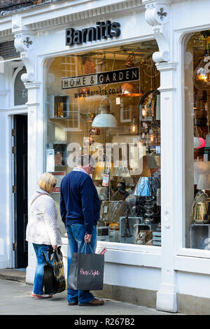 Mature couple standing outside Barnitt's home & garden shop, window shopping & viewing lamps in lighting display - York, North Yorkshire, England, UK. Stock Photo