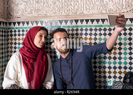 Young Muslim couple smiling and taking selfie with smart phone Stock Photo
