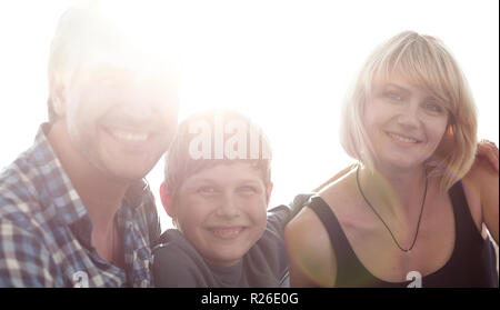 Parents and their son sit huddled in the living room and smiling Stock Photo