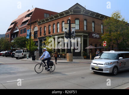 A bicyclist, automobiles and a pedestrian on 10th Street at the east end of Pearl Street Mall in Boulder, CO. zTrip is a taxi company in Boulder. Stock Photo