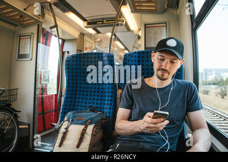A young man listens to a music or podcast while traveling in a train. Stock Photo