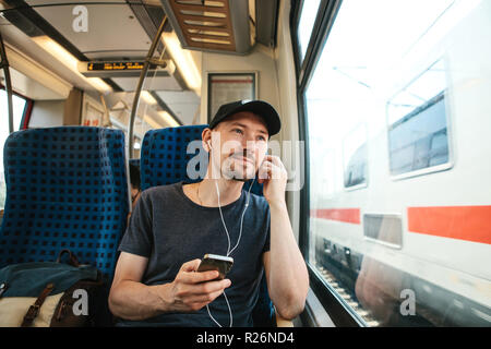 A young man listens to a music or podcast while traveling in a train. Stock Photo