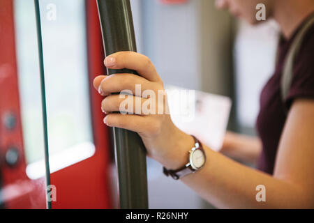 A tourist girl or a student inside the subway or train looks at a map and waits for its stop to go outside. Selective focus on the hand. Travel concept. Stock Photo