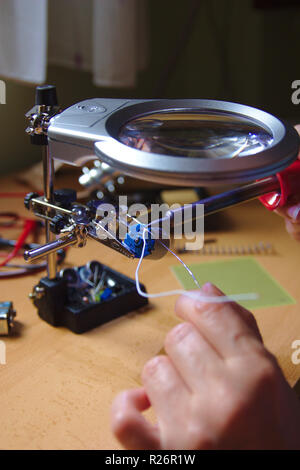 Workshop of a technician dedicated to electronic welding while working on the connection of a small device Stock Photo