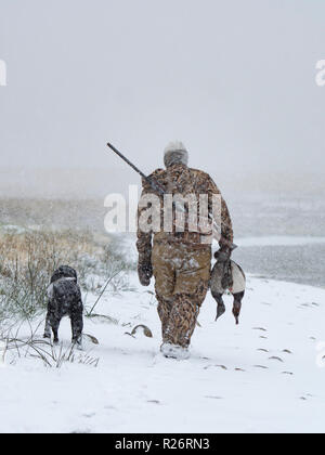 A duck hunter and his dog in a snow storm Stock Photo