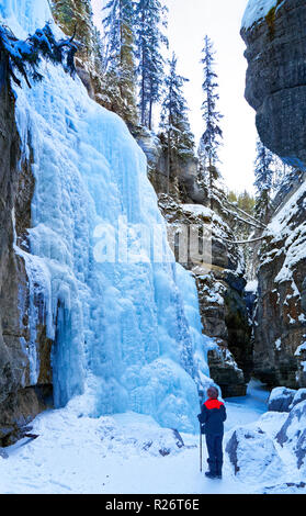 42,749.08968 Woman in a deep winter snowy frozen river canyon (Maligne River Canyon) looking up at frozen icy walls & icefalls Stock Photo
