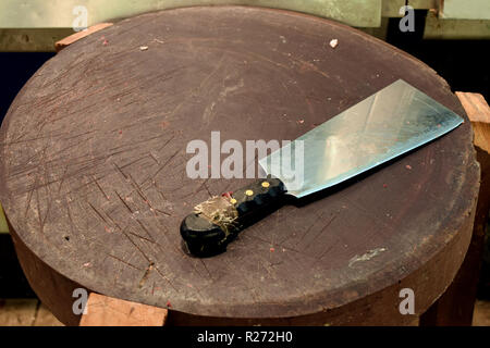 Bloody meat cleaver on wooden butchers cutting board. Stock Photo