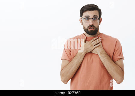 Waist-up shot of concerned charming gay friend in glasses with beard gasping from shock and empathy hearing terrible news standing surprised and worri Stock Photo