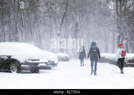 People walking through city street covered with snow during heavy snowfall. Blizzard in town at winter. Natural disasters, snow storm. Stock Photo