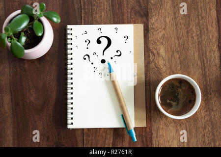 question mark symbols in notebook laying on office desk. flat lay view. Stock Photo
