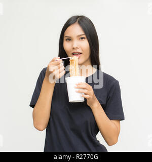 Young beautiful asian woman eating yummy hot and spicy instant noodle using chopsticks isolated on gray background.Unhealthy concept Stock Photo