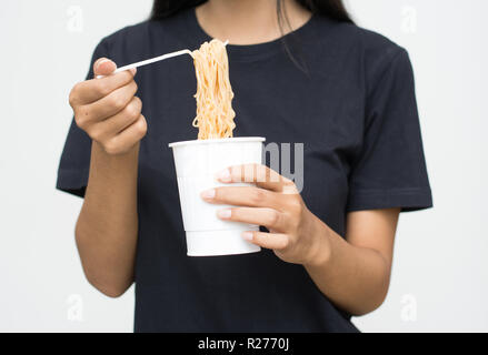 Hand of a woman holding a plastic fork with cooked instant noodles from paper cup. Stock Photo