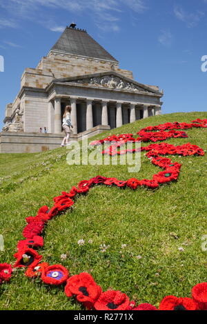Vertical image of bright red yarn poppies laid out in beautiful pattern on hillside below Shrine of Remembrance on Anniversary of Armistice of WWI. Stock Photo
