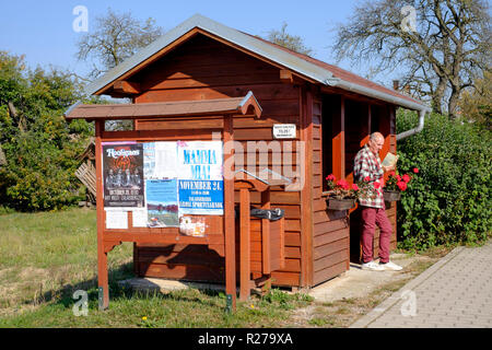 male reading at an ornate wooden bus shelter decorated with flowers in a rural village in zala county hungary Stock Photo