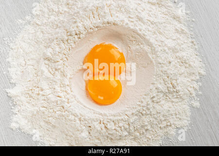 egg yolks on white flour for dough, top view on table. Stock Photo