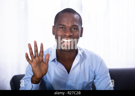 Portrait Of A Happy Young Man Waving His Hand Stock Photo