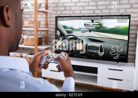 Close-up Of An African Man Playing Racing Game With Joystick On Television Stock Photo