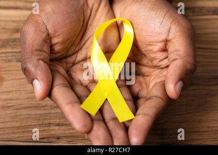 Person's Hand Holding Ribbon To Support Childhood And Bladder Cancer Stock Photo