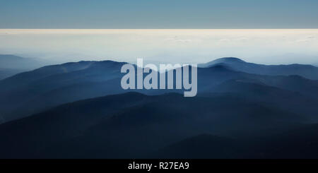 Peaceful blue nature background with foggy Bucegi mountains in Carpathians seen from Cota 2000, Sinaia resort, Romania Stock Photo