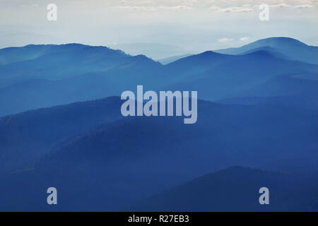 Peaceful blue nature background with foggy Bucegi mountains in Carpathians seen from Cota 2000, Sinaia resort, Romania Stock Photo