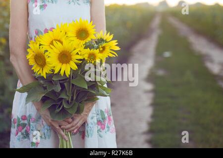 girl holding a huge bouquet of sunflowers in their hands Stock Photo