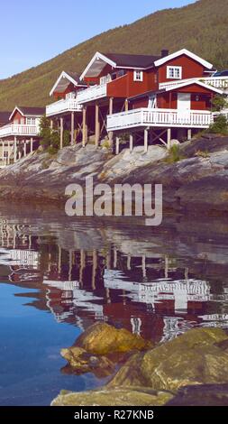 rorbuer - traditional norwegian red wooden house to stand at the lakeside and mountains in the distance, norway Stock Photo