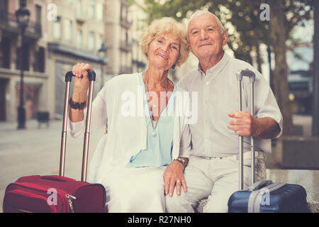 Happy loving senior spouses enjoying joint vacation sitting on bench Stock Photo