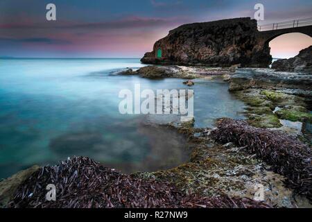 Rocky arch with green door in Cala Major, Mallorca, Spain at sunsest Stock Photo