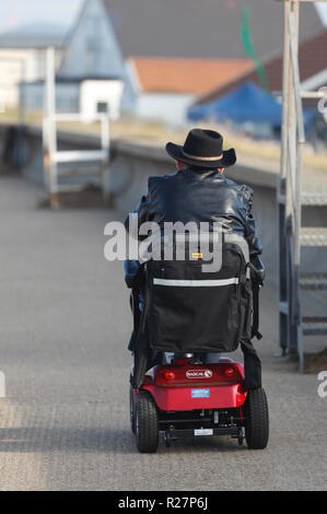 Man riding a mobility scooter on the promenade at Heacham. Stock Photo