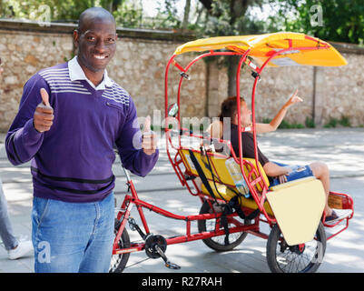 Portrait of African American driver of pedicab offering touristic tour of city Stock Photo