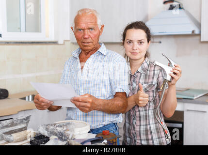 Happy young woman and her elderly father discussing work manual on mixer tap installation during overhaul at home Stock Photo