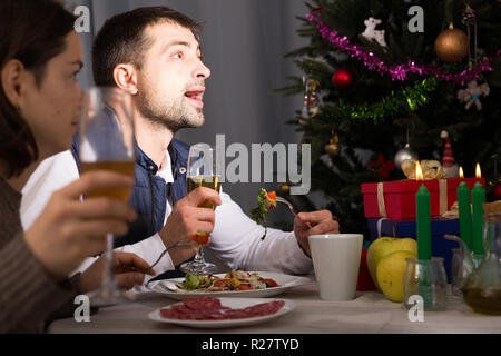 Family couple having christmas dinner with champagne and watching tv Stock Photo
