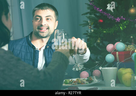Family couple having christmas dinner with champagne and watching tv Stock Photo