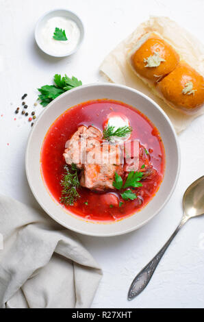 Borscht, Red Soup Made of Beetroot and Vegetables with Pork Ribs and Sour Cream Served with Garlic Rolls, Traditional Dish of Ukrainian, Russian and P Stock Photo